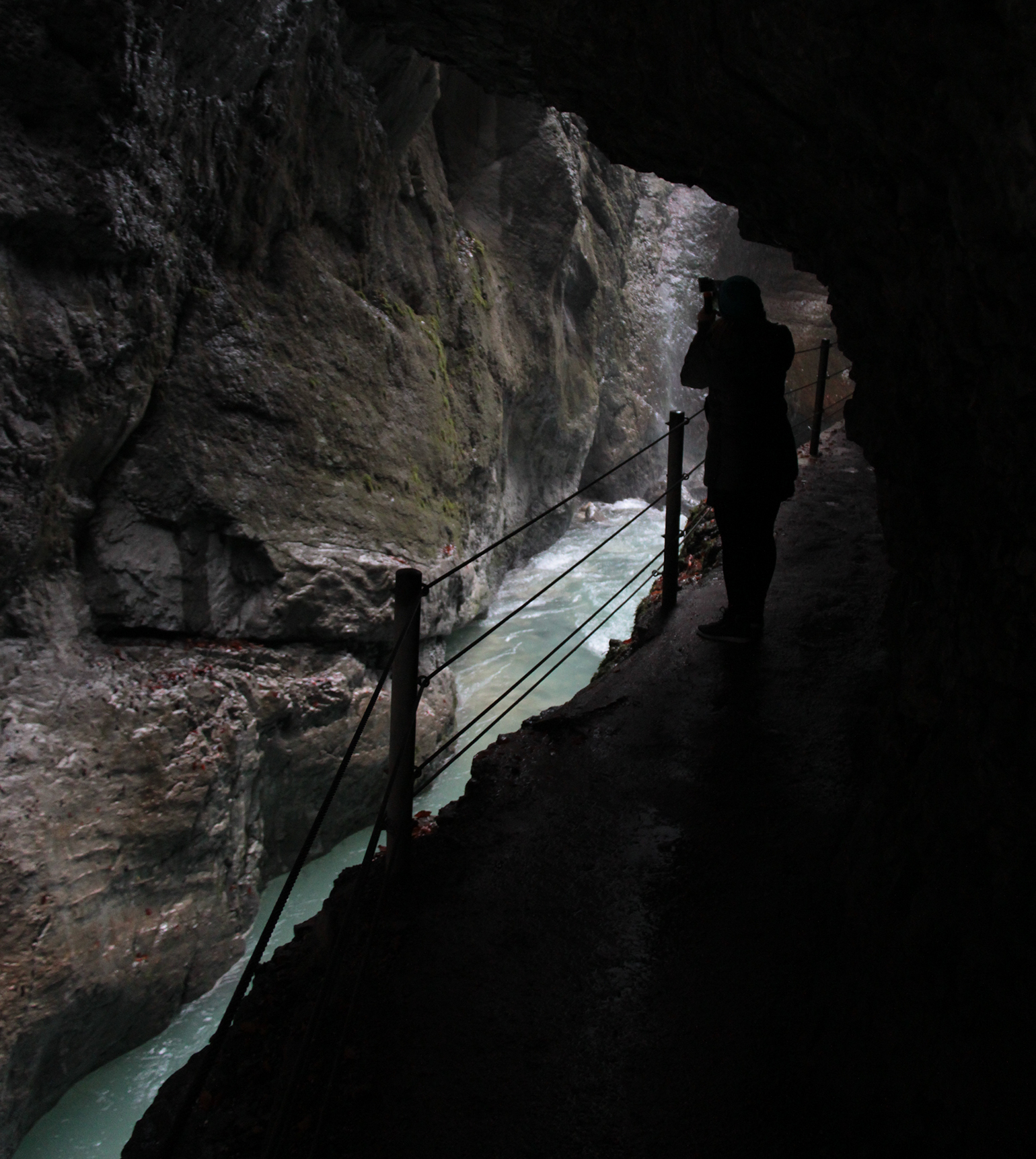 A trilha entre os paredões de pedra intercala trechos iluminados ou mais escuros em Partnach Gorge